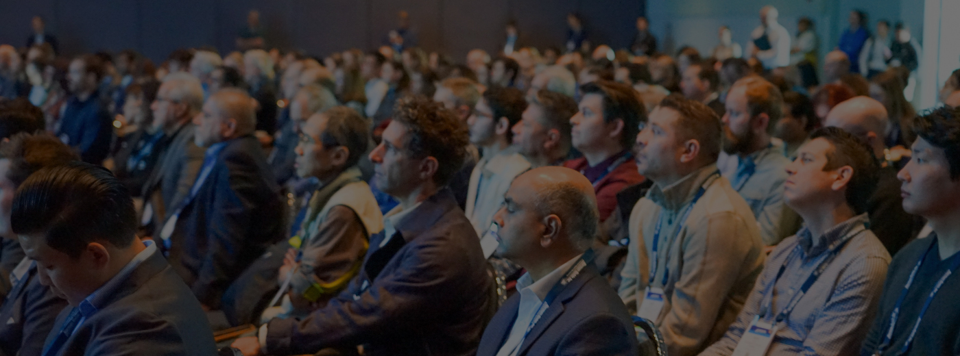 A large crowd of people seated in a conference room, engaged in a presentation or discussion