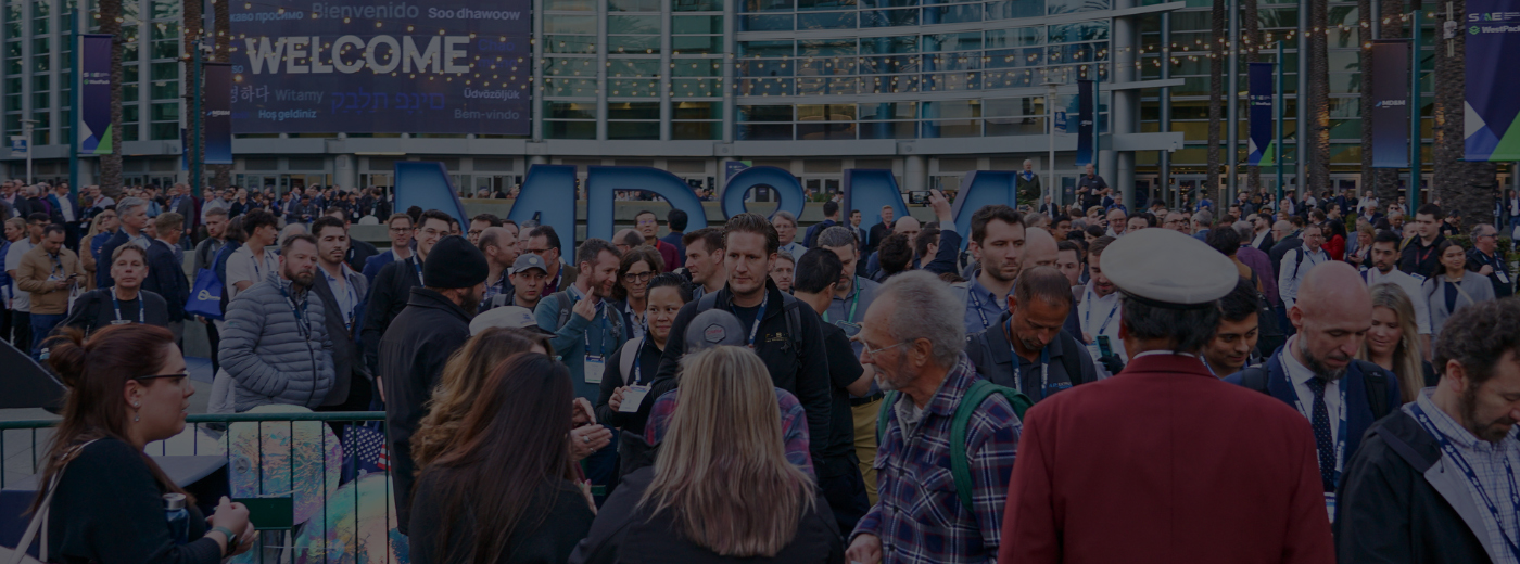 A large crowd of people gathered outside a convention center, waiting to enter the event