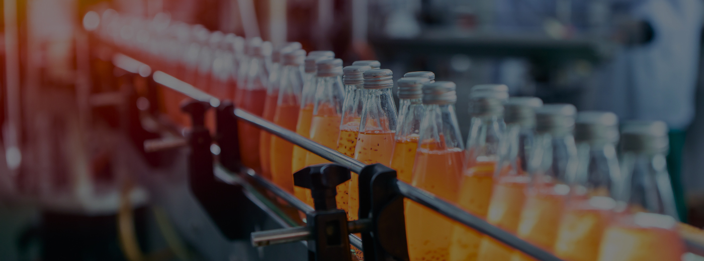 Bottles of orange juice moving along a conveyor belt in a production facility
