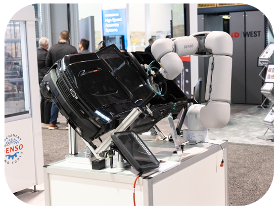 A sleek robot exhibited at a trade show, attracting attention from visitors interested in robotics and innovation