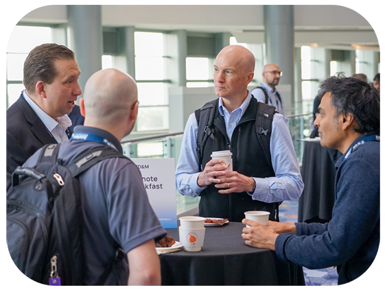 Four men engaged in conversation at a table during an event, sharing ideas and insights