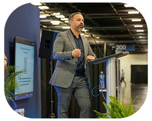 A man in a suit delivers a speech at a convention, standing confidently at a podium photo