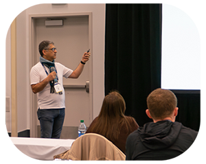 A man presenting to an audience, engaging with the group while using visual aids to enhance his messagephoto