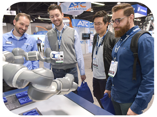 Four men observe a robot at an exhibit, engaged in discussion about its features and technology