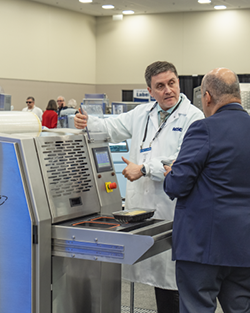 A man is explaining his machine to an attendee
