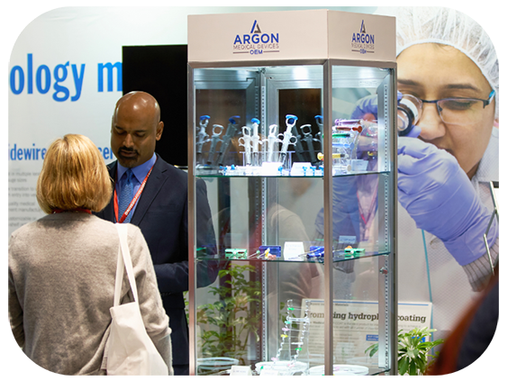 A man and woman stand before a display case, observing the displayed items closely and discussing them