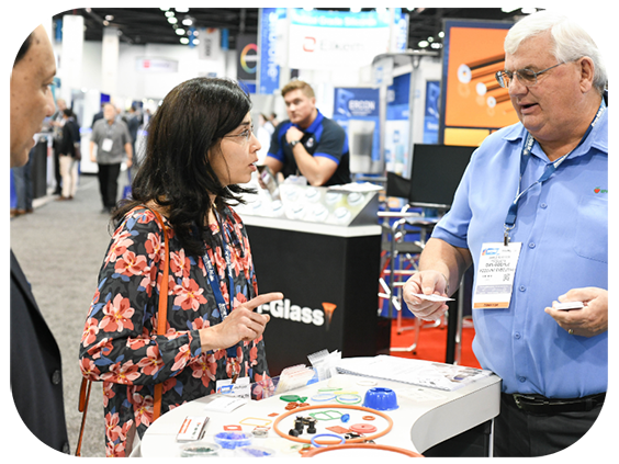 A man and woman engaged in conversation at a bustling trade show, surrounded by various booths and attendees